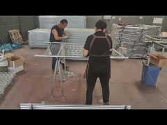 作業員は、チェーンリンクフェンスとフレームチューブを接続するためにワイヤーを使用しています。